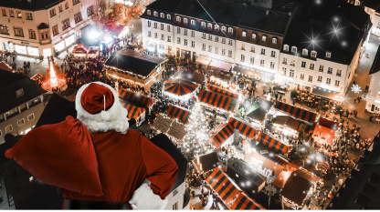 Ein Weihnachtsmann von Hinten fliegt über den abendlichen Saarbrücker Weihnachtsmarkt